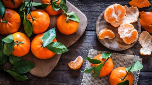 Top view of fresh organic mandarins on rustic wooden table. One mandarin is peeled. Predominant colors are orange and brown. DSRL studio photo taken with Canon EOS 5D Mk II and Canon EF 100mm f/2.8L Macro IS USM